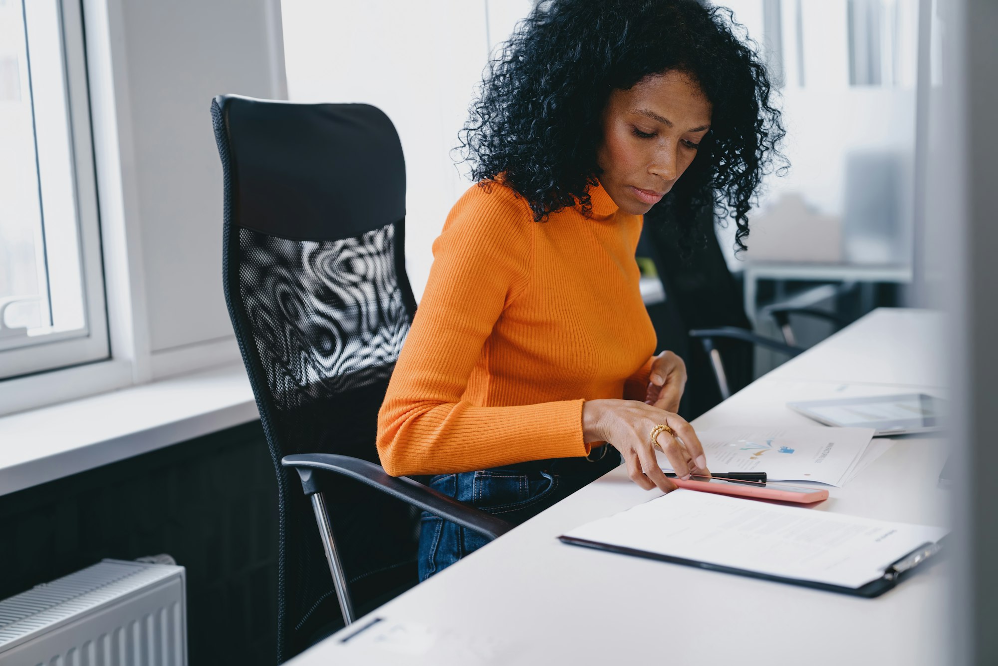 Diligent Black female accountant in her 30s, managing ledgers in a modern